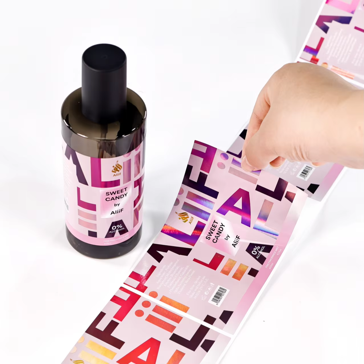 Hand holding holographic perfume label strip next to bottle