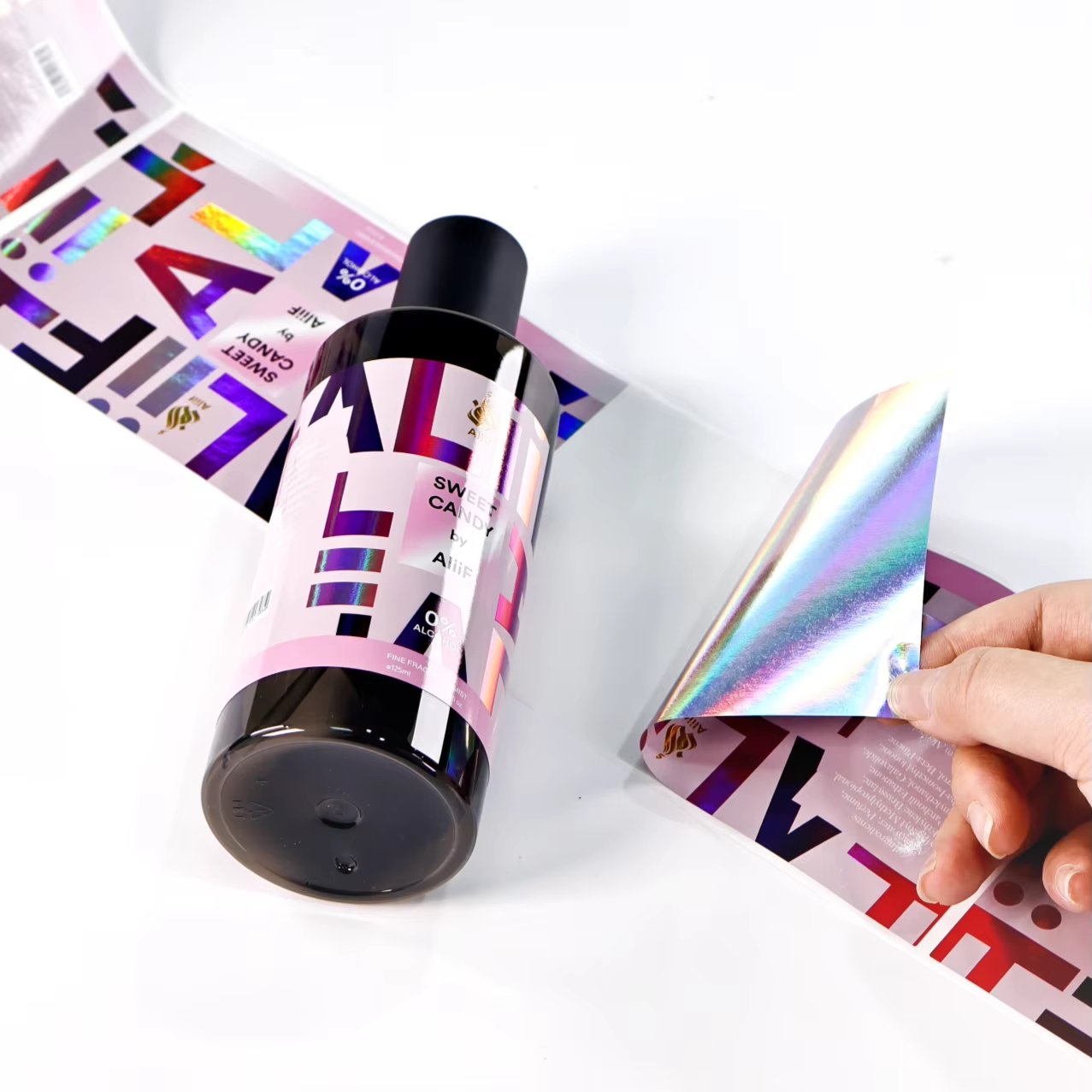 Holographic perfume label on black bottle with pink typography