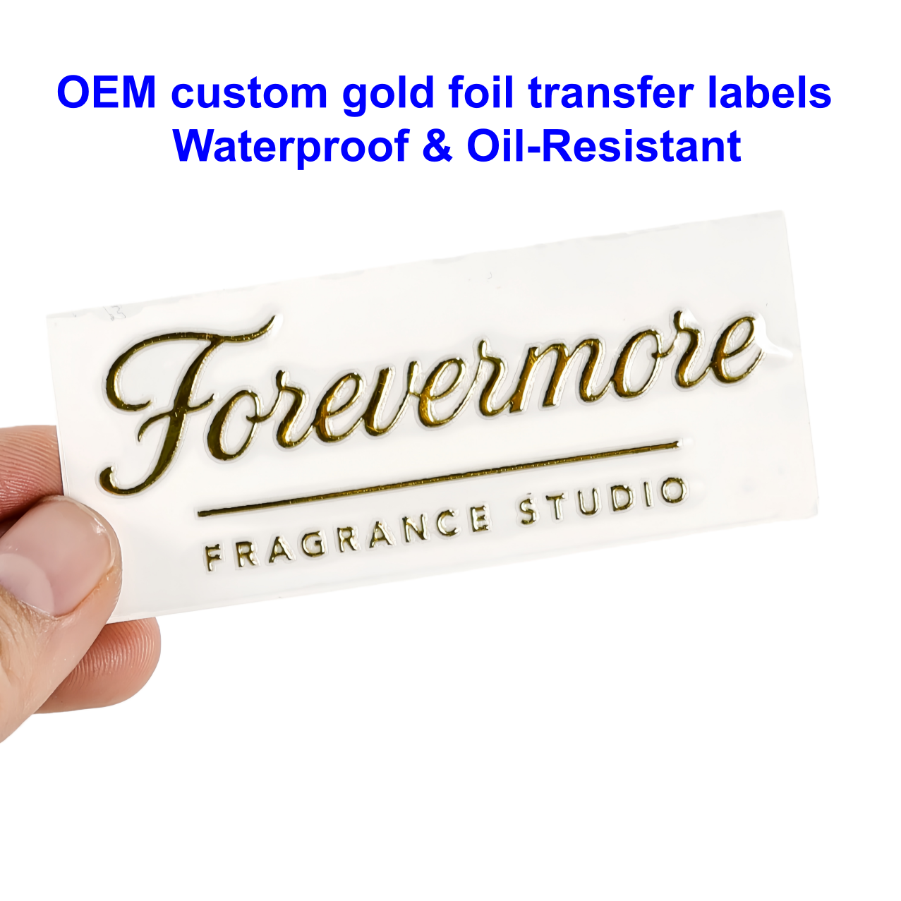 Custom gold foil transfer label held between fingers, showing metallic script and clean edges
