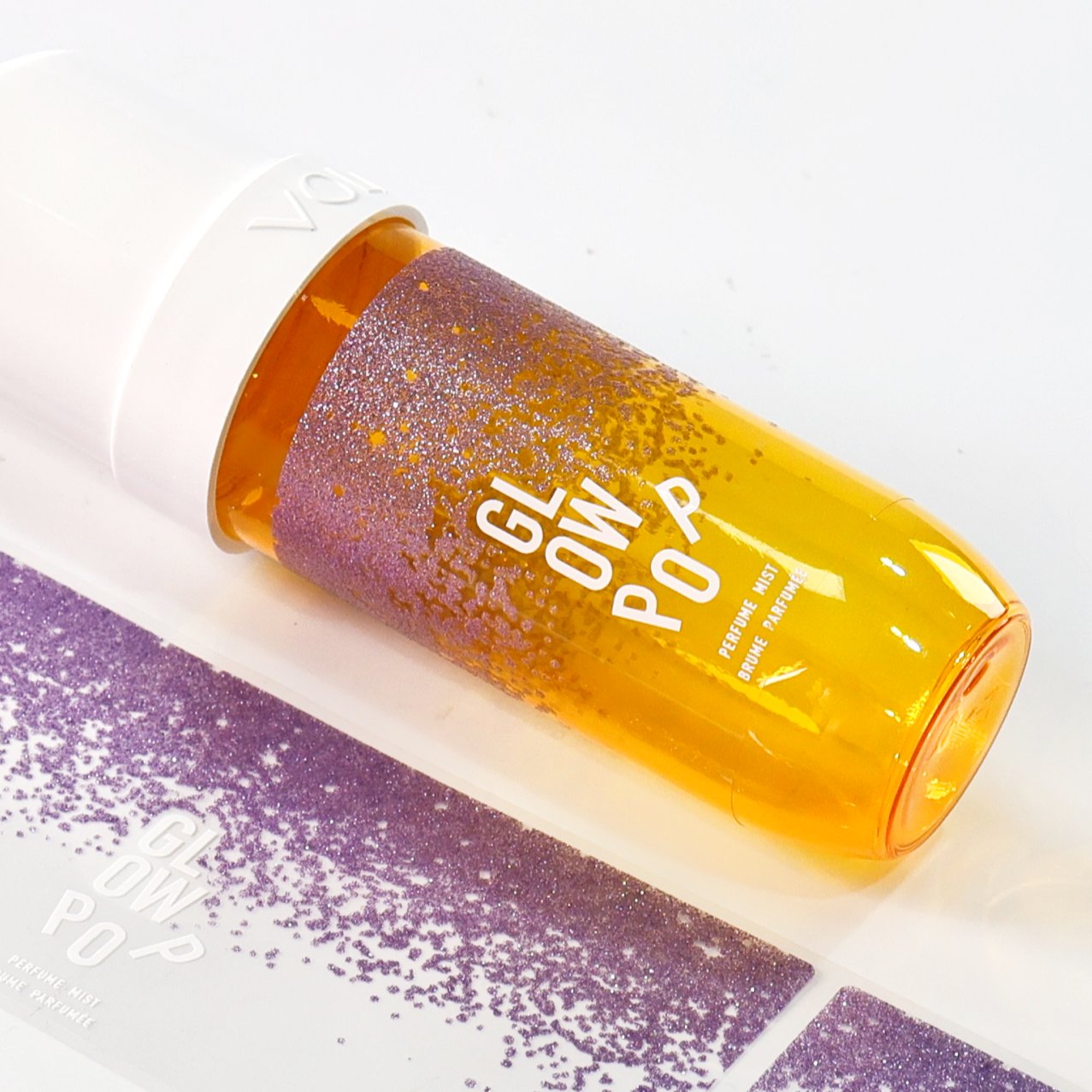Perfume mist bottle with a purple glitter label and matching roll