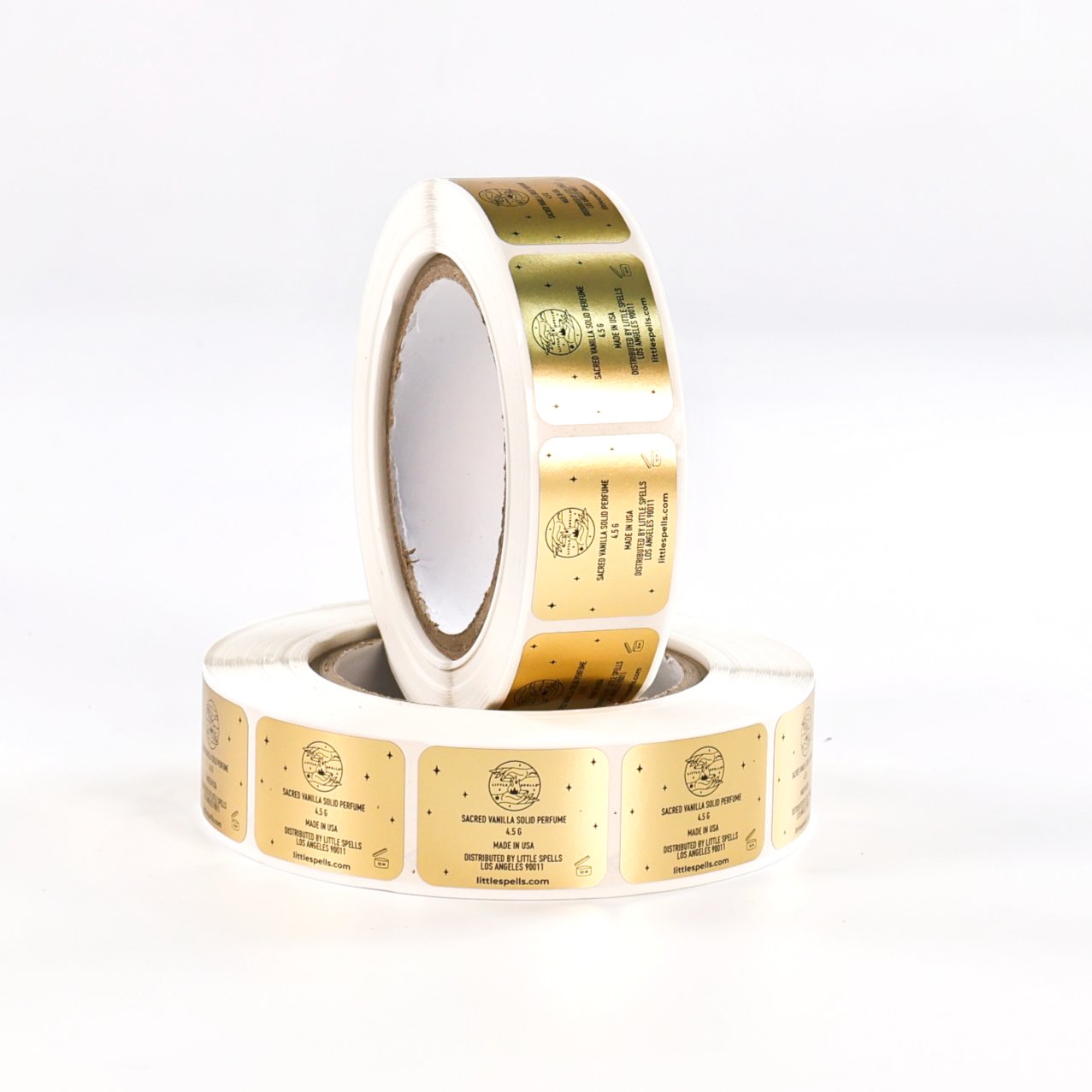 Two rolls of gold-foil solid perfume labels with black print, wound and ready for application