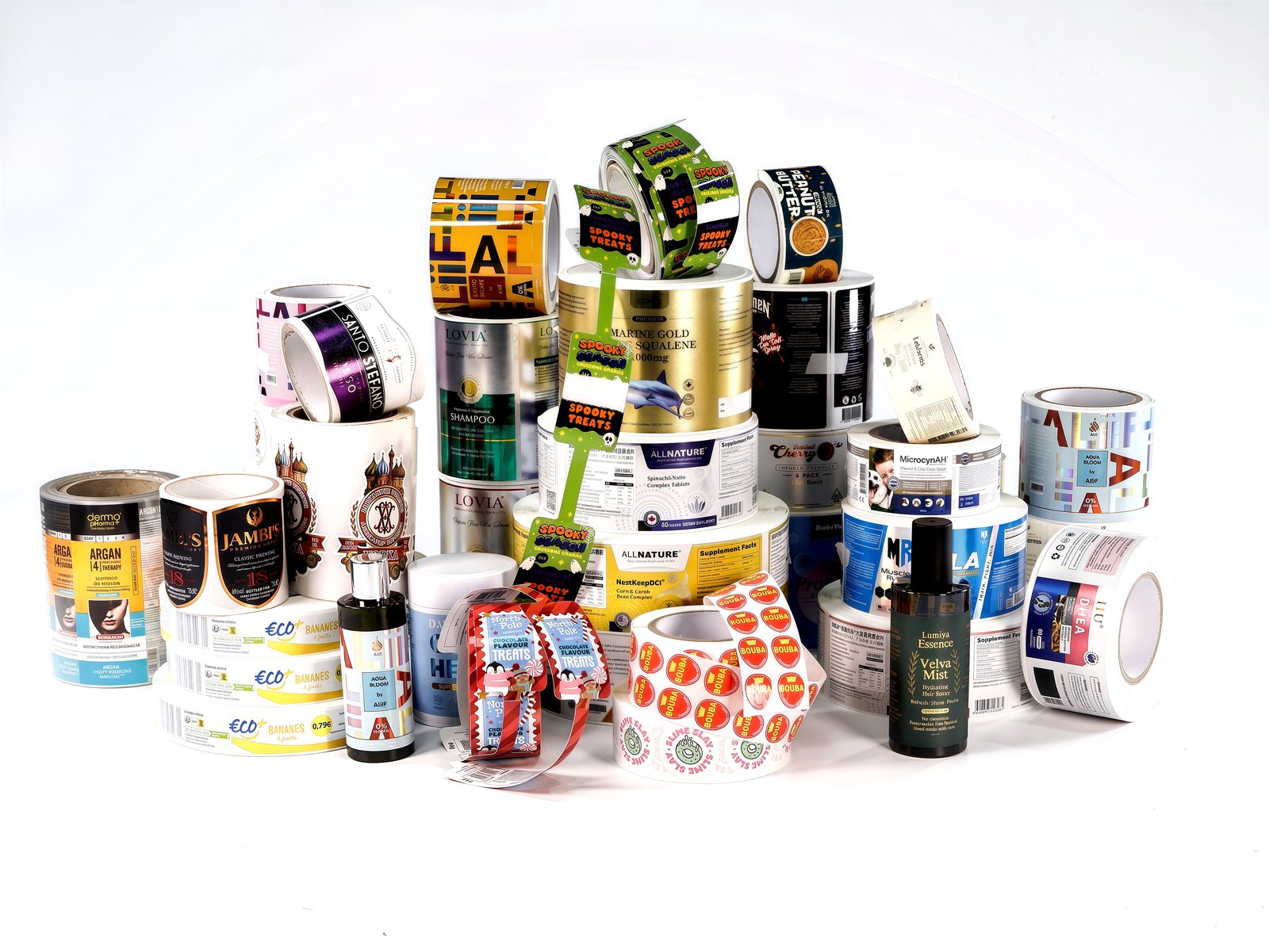 Rolls of printed labels for wine, spirits, cosmetics and supplements stacked on a white studio background
