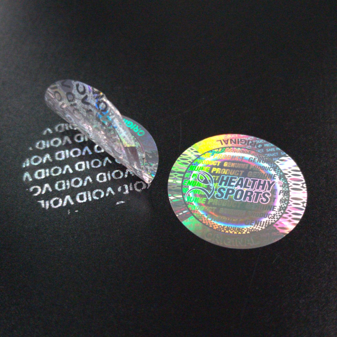 Transparent HEALTHY SPORTS laser-engraved holographic label next to the VOID pattern revealed on the black surface after peeling
