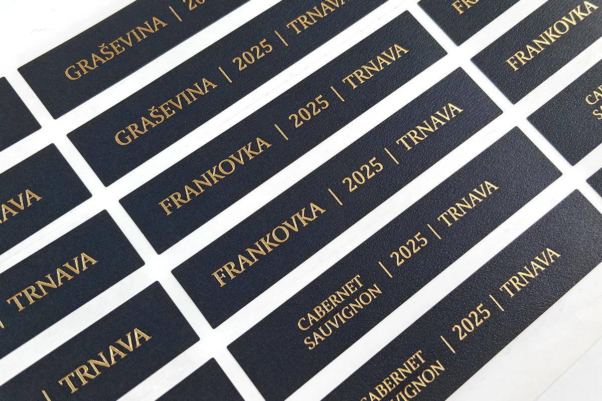 Black specialty paper label sheet: multiple gold foil labels neatly arranged